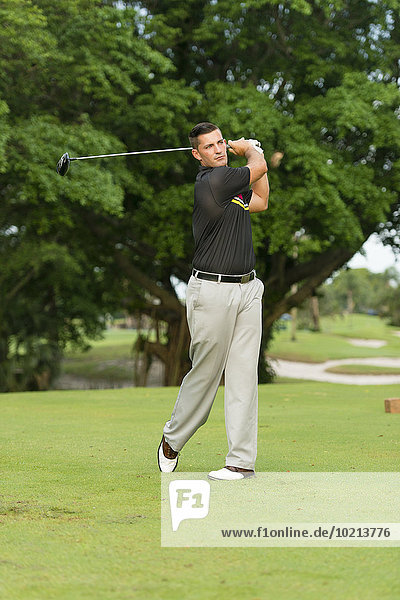 Caucasian man swinging club on golf course