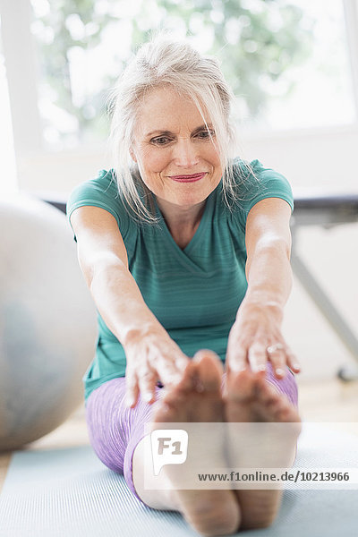 Older Caucasian woman stretching in gym