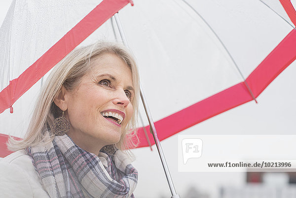 Older Caucasian woman standing under umbrella