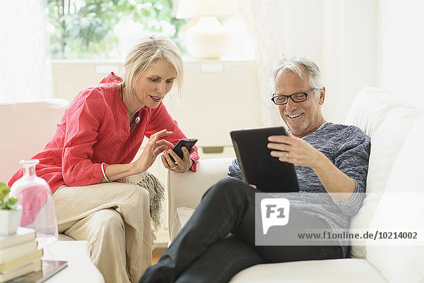 Older Caucasian couple using technology in living room