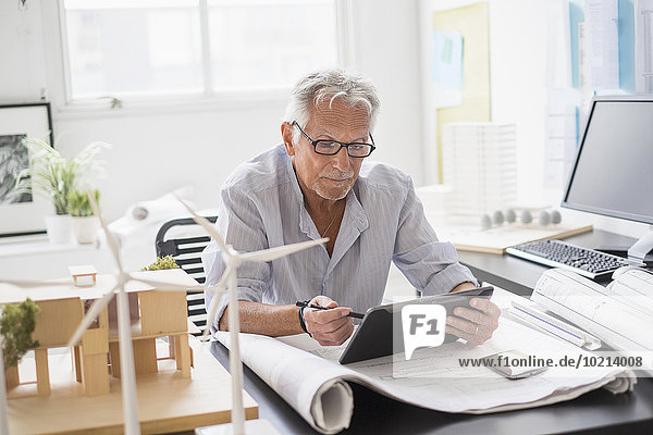 Older Caucasian architect using digital tablet in office