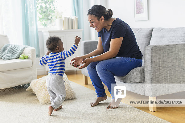 Mixed race mother playing with baby son in living room