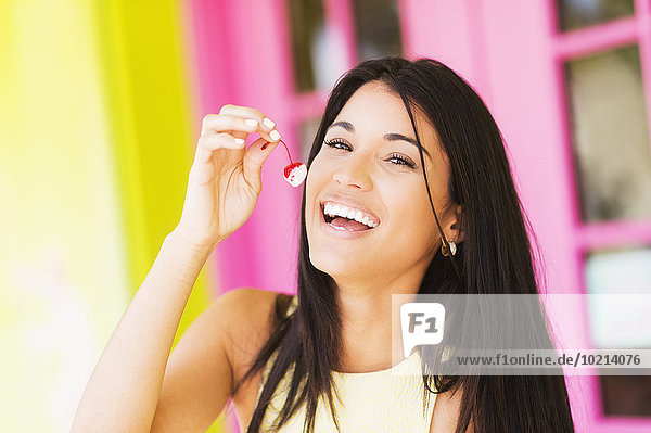 Hispanic woman eating cherry outdoors