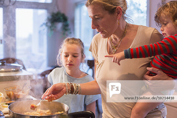 Caucasian mother and children cooking in kitchen