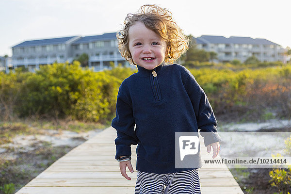 Caucasian baby boy on wooden walkway on beach