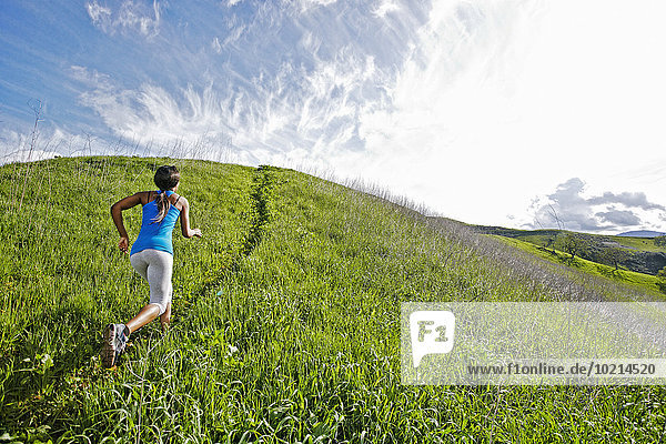 Black athlete running on rural hillside