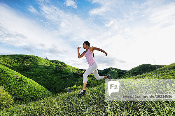 Black athlete running on rural hillside