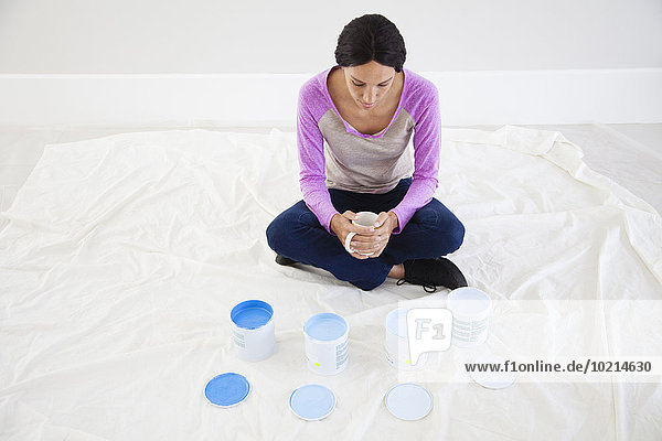 Mixed race woman examining paint samples in new home