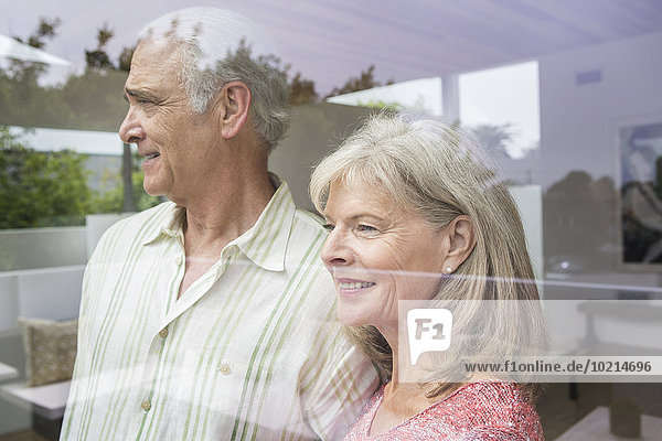 Older Caucasian couple looking out window