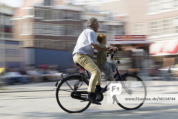 Blurred view of father and son bicycling on city street