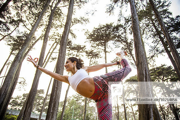 Hispanic woman practicing yoga in forest