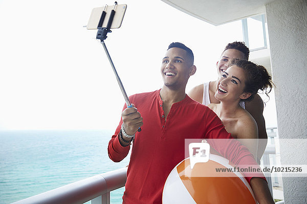 Smiling friends taking selfie on balcony