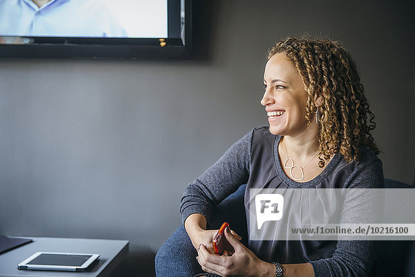 Mixed race businesswoman laughing in office lobby