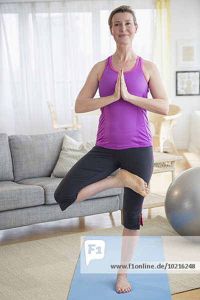 Caucasian woman practicing yoga in living room