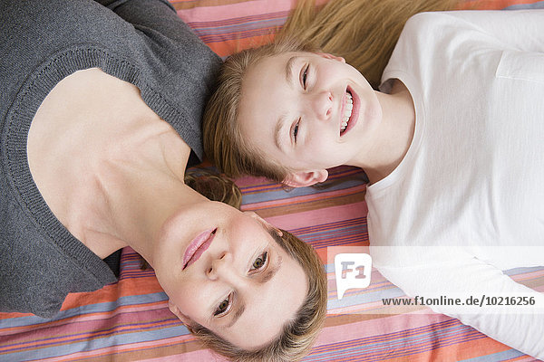 Caucasian mother and daughter laying on blanket