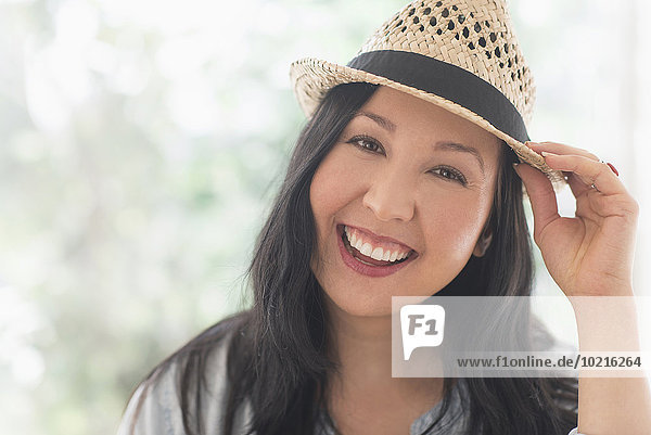 Smiling mixed race woman wearing straw hat