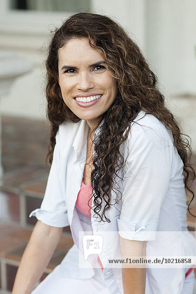 Smiling Hispanic woman sitting outdoors