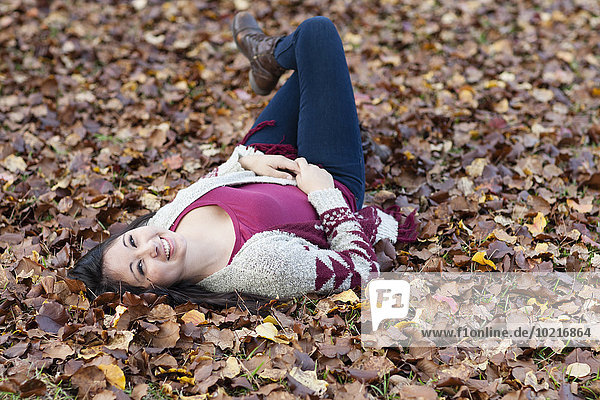 Hispanic teenage girl laying in autumn leaves