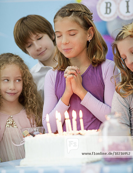 Girl wishing over birthday cake at party