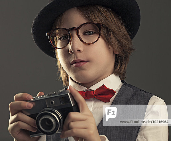 Close up of boy in hat photographing with vintage camera