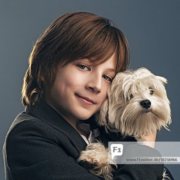 Close up of boy in suit holding dog