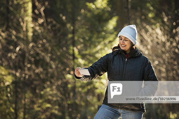 Hispanic woman taking selfie in forest
