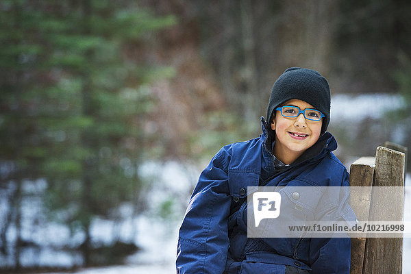 Hispanic boy sitting on chair in forest