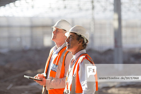 Caucasian architects using digital tablet at construction site