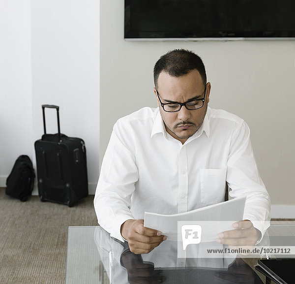 Hispanic businessman reading paperwork in office