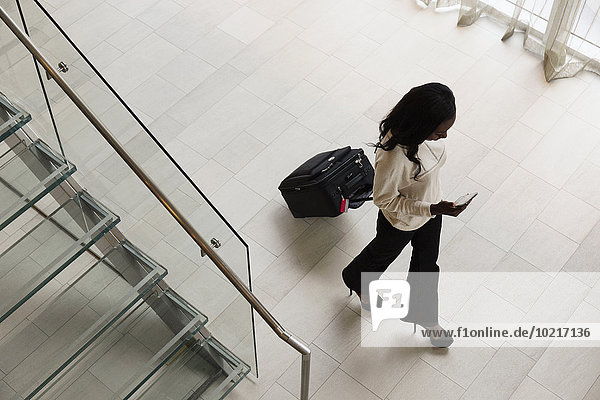 High angle view of businesswoman rolling luggage in hotel lobby