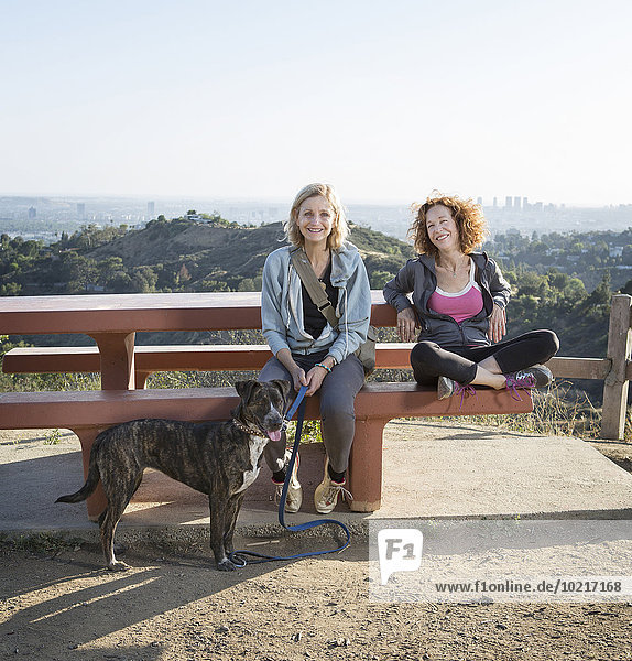 Caucasian women sitting with dog on hilltop
