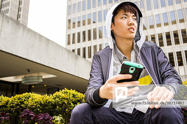 Asian man using cell phone in city