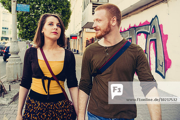 Caucasian couple walking on city sidewalk