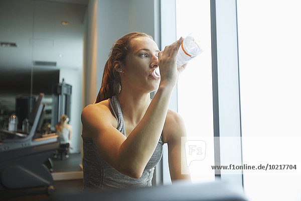 Woman drinking water bottle in gym