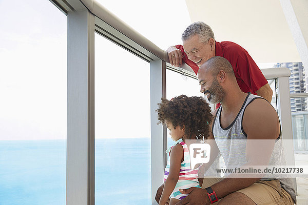 Multi-generation family overlooking ocean from balcony