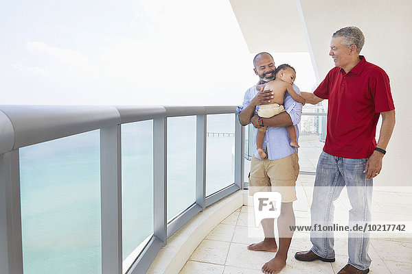 Three generations of men standing on balcony