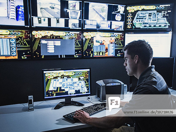Hispanic security guard watching monitors in control room