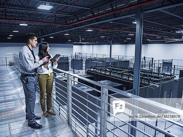 Business people examining server room from balcony