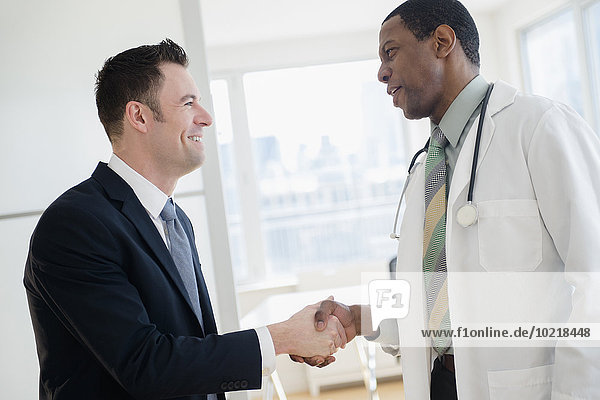 Businessman and doctor shaking hands in office