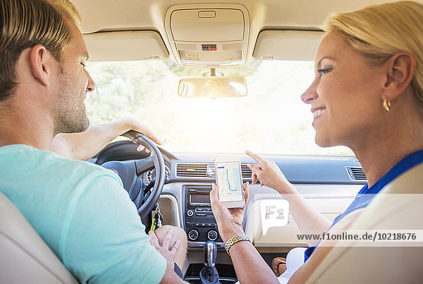 Caucasian couple using cell phone navigation in car
