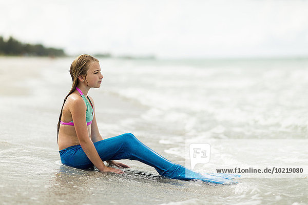 Caucasian girl wearing mermaid fin on beach