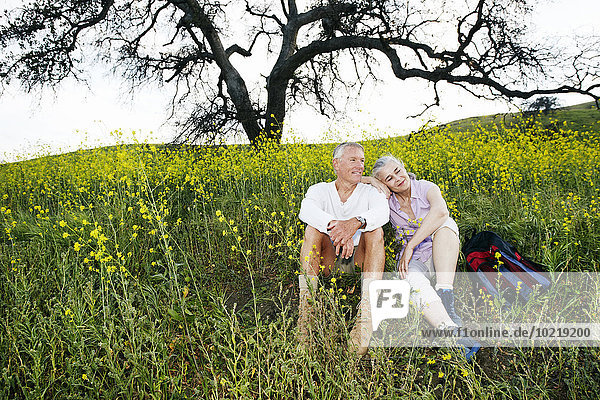Caucasian couple sitting in tall grass