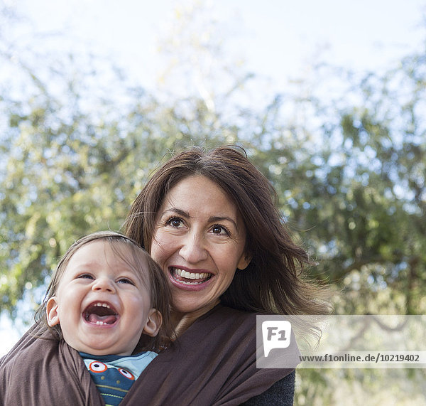 Hispanic mother wearing son in carrier outdoors