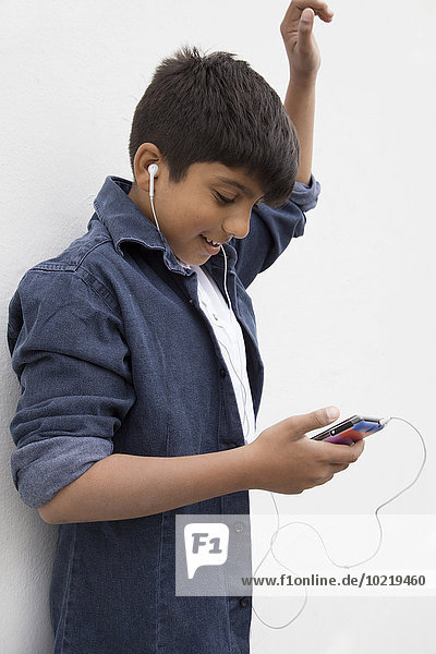 Asian boy listening to earbuds with cell phone