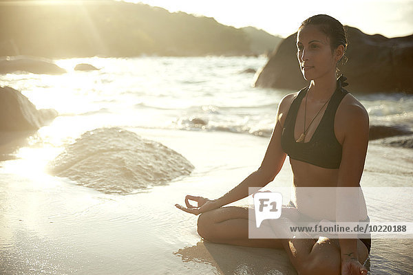 Seychellen  Frau meditiert an der Strandpromenade
