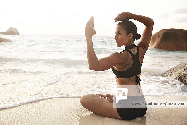 Seychellen  Frau bei Yoga-Übungen am Meer