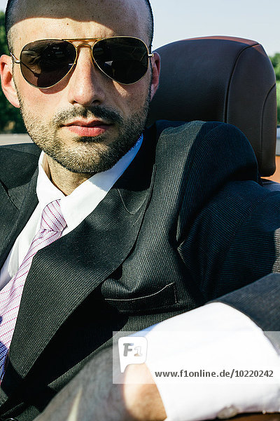 Portrait eines Geschäftsmannes mit Sonnenbrille im Cabriolet
