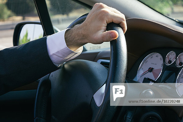 Hand of a businessman on steering wheel of his car