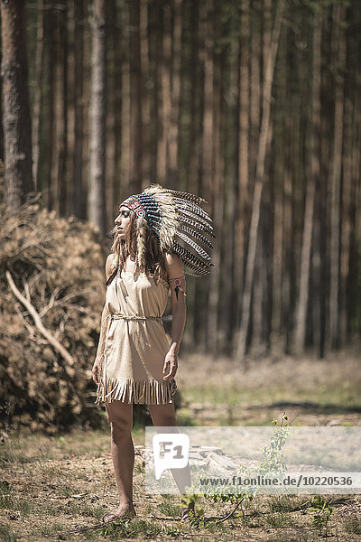 Junge Frau verkleidet als Indianerin im Wald stehend