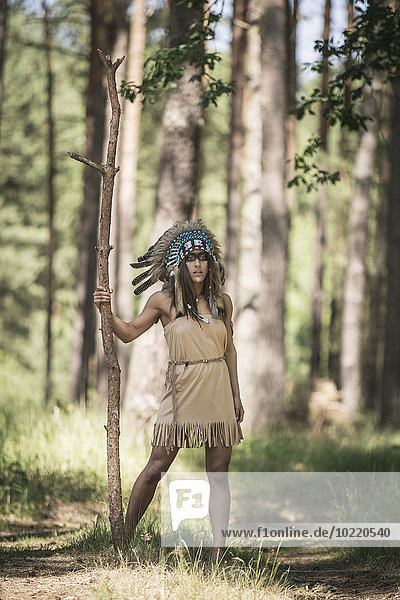 Junge Frau verkleidet als Indianerin im Wald stehend